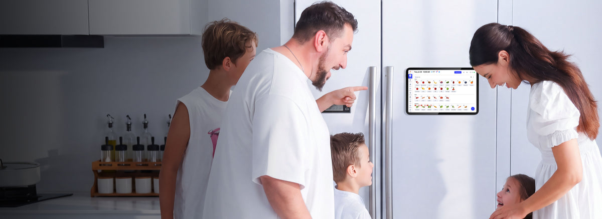 Happy family looking at grocery inventory list on Everblog FridgeCal tablet mounted on white side-by-side fridge in bright kitchen